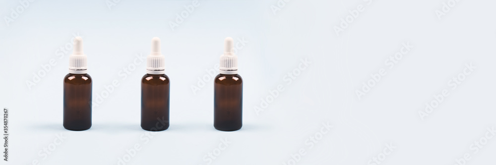 Banner with bottles of essential oil, collagen or hyaluronic acid on light blue background. Mockup and copyspace for your design or text. Modern beauty and apothecary concept Banner with bottles of essential oil, collagen or hyaluronic acid on light blue background. Mockup and copyspace for your design or text. Modern beauty and apothecary concept