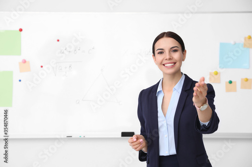Young teacher near whiteboard in modern classroom. Space for text