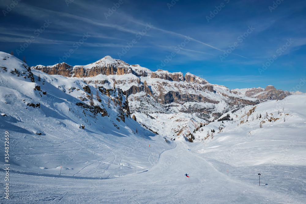 View of a ski resort piste with people skiing in Dolomites in Italy. Ski area Arabba. Arabba, Italy