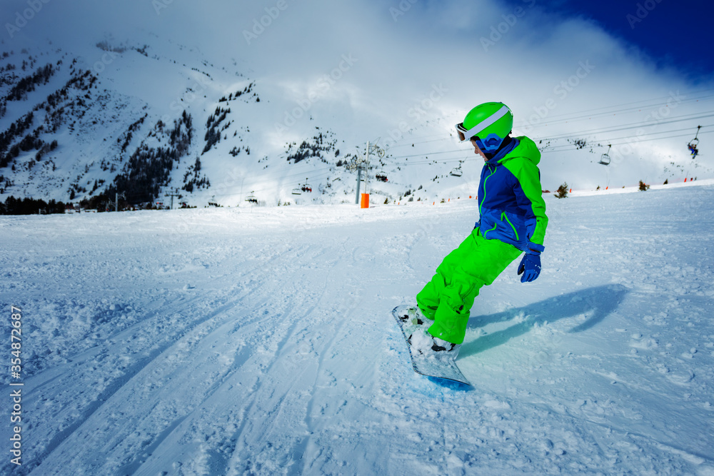 Action dramatic portrait of a boy on snowboard ride downhill view from behind on the slope track Action dramatic portrait of a boy on snowboard ride downhill view from behind on the slope track
