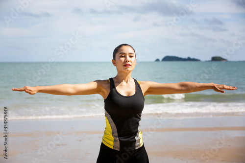 A woman in sportswear are exercising on the beach in summer.