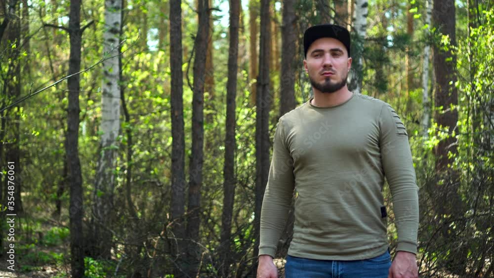 Attractive man in a baseball cap with a beard lost his way with the forest and stands looking around. Get lost in a walking trip. Attractive man in a baseball cap with a beard lost his way with the forest and stands looking around. Get lost in a walking trip.