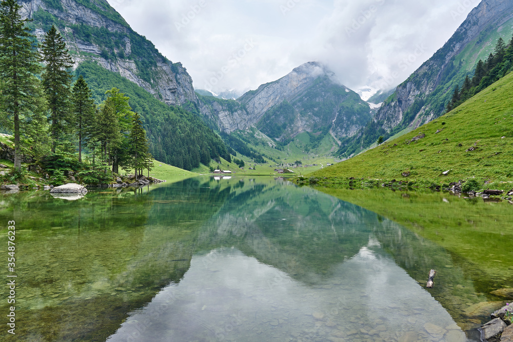 Landscape panorama from Seealpsee, Alpstein range of the canton of Appenzell, Switzerland. Green nature, mountains and their reflections on the lake.