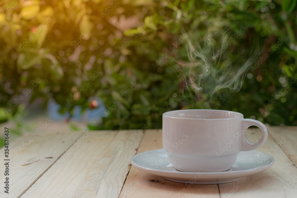 A coffee cup placed on a wooden background with a tree  bokeh