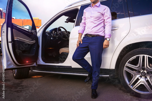 Bright man stands next to the road premium white car, the reflection of the sky 