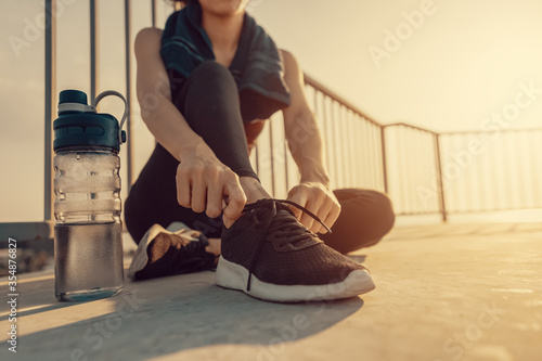 Woman tying jogging shoes on the ground in the morning .
