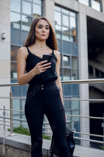 Business Woman With Phone Near Office. Portrait Of Beautiful Smiling Female In Fashion Office Clothes Talking On Phone While Standing Outdoors. Phone Communication. High Quality Image.