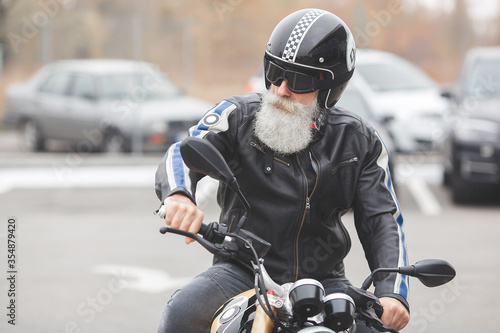 Old stylish man driving the motorcycle. Brutal male.