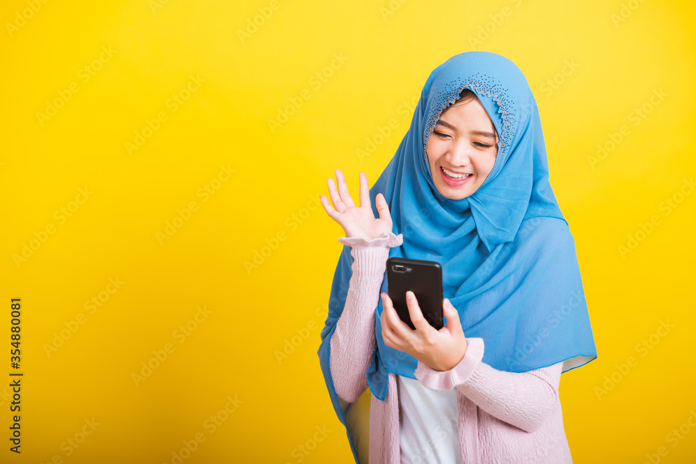 Fotografia do Stock: Asian Muslim Arab, Portrait of happy beautiful young  woman Islam religious wear veil hijab funny smile she selfie or video call  mobile smart phone raise hand say hello isolated