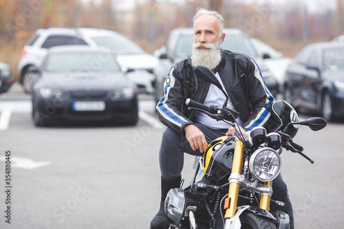 Old stylish man driving the motorcycle. Brutal male.