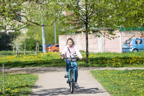 Wallpaper Mural Teenage girl riding on pathway in summer park on blue bicycle, front view Torontodigital.ca