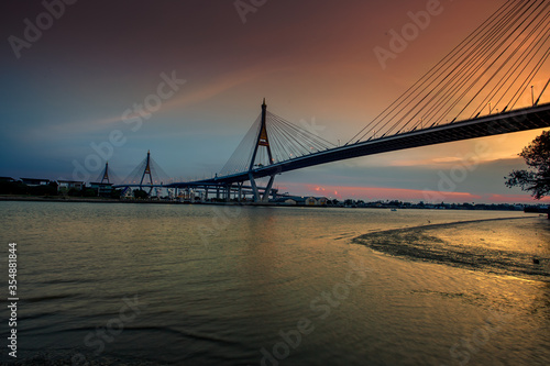 The blurred background of the twilight evening by the river, the natural color changes, the bridge over the river (Bhumibol Bridge) is one of the major transportation bridges in Bangkok, Thailand © bangprik