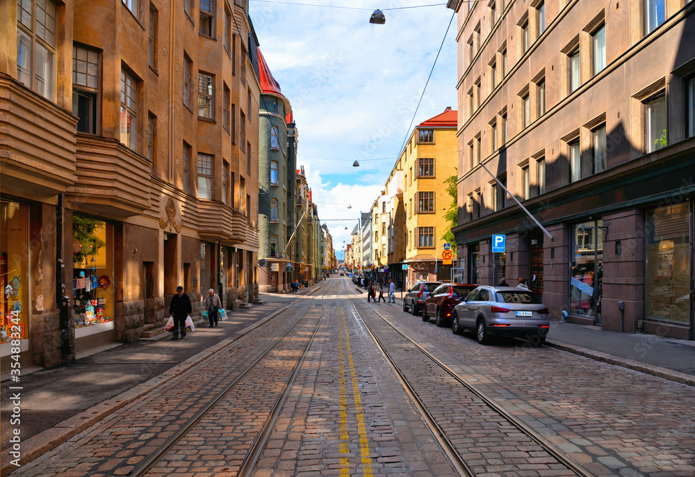 street with cars, people, colorful old buildings and architecture and cloudy blue sky in Helsinki, Finland