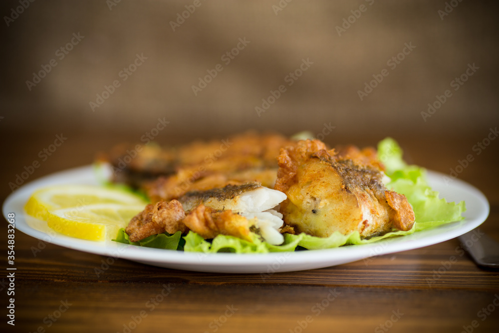 fried hake fish in batter with lettuce and lemon in a plate fried hake fish in batter with lettuce and lemon in a plate