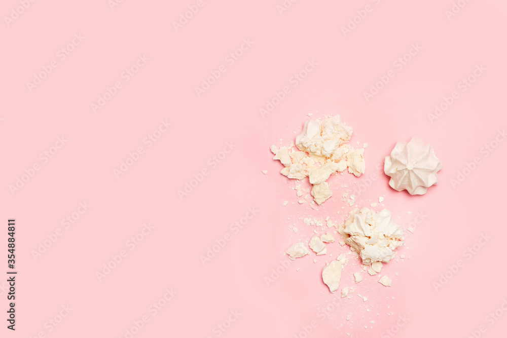 Malvaviscos merengue blancos desmenuzado y entero en forma de rosa sobre un fondo rosa liso y aislado. Vista superior. Copy space