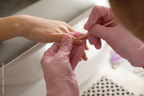 Professional manicurist working with client in beauty salon, closeup photo