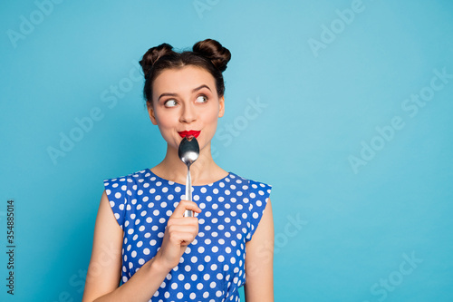 Photo of beautiful lady holding metal spoon in mouth look up empty space dreaming about tasty food wear dotted blouse shirt white isolated blue color background photo