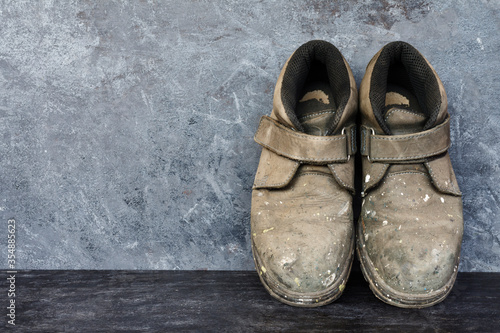 Dirty old shoes on black wooden floors and gray walls.