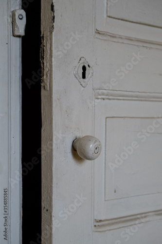 Details of a white painted wooden door of an empty abandoned old building