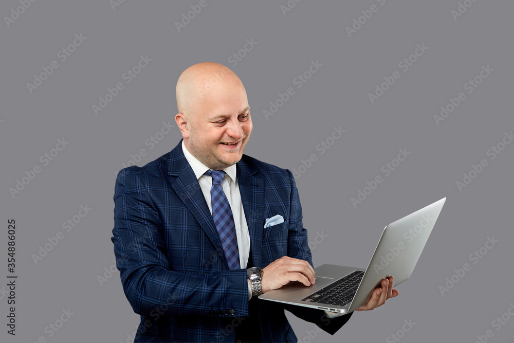 A solid adult bald man laughs with a laptop in his hands. A solid adult bald man laughs with a laptop in his hands.