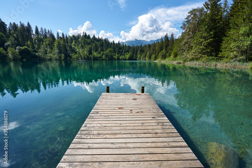 Fototapeta Naklejka Na Ścianę i Meble -  Landscape panorama of Crestasee - Lake Cresta in June, municipalities of Flims and Trin in the Grisons, Switzerland. Wooden dock on the lake.      