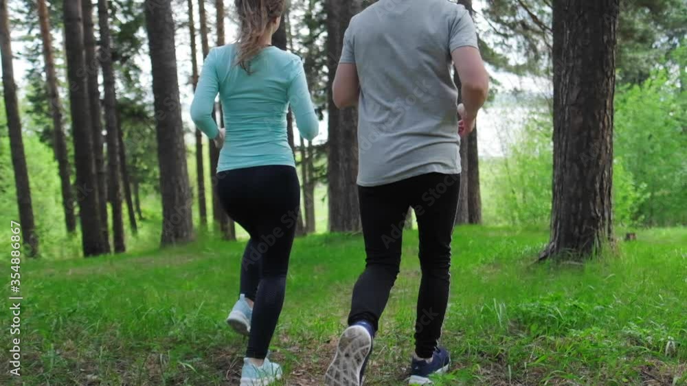 Sportive young people running. Couple work out and run up the hill in the park during the day Sportive young people running. Couple work out and run up the hill in the park during the day