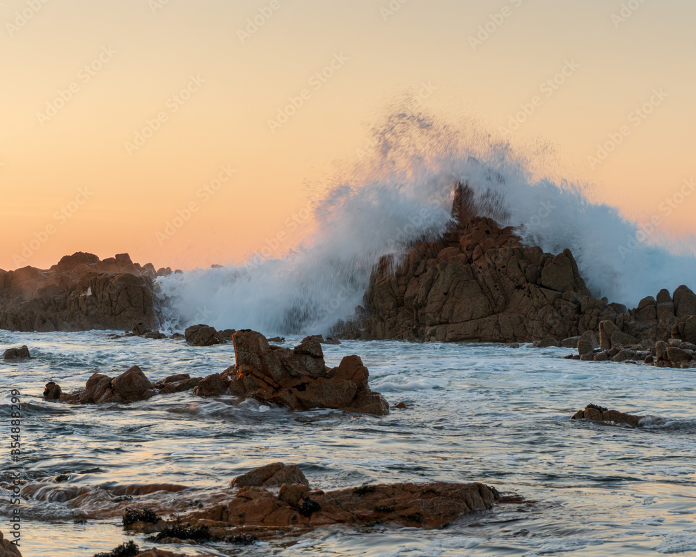 waves crashing on rocks with sunset in Guernsey