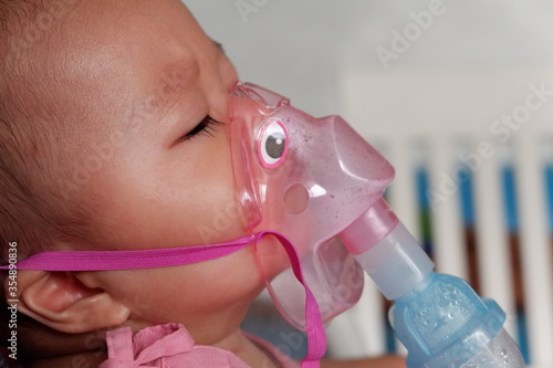 Sick boy inhalation therapy by the mask of inhaler. Boy is sick with Respiratory Syncytial Virus. Patient Boy use inhalation with Nebulizer mask at hospital. The baby are spraying bronchodilators .