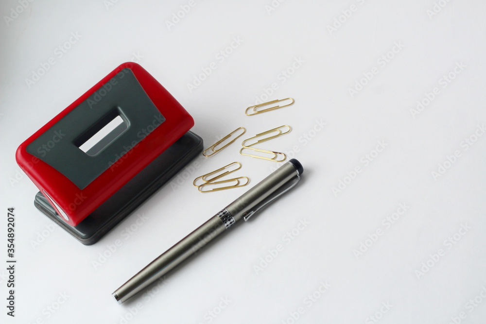 stationery, hole punch, paper clips and pen for writing on a white background stationery, hole punch, paper clips and pen for writing on a white background