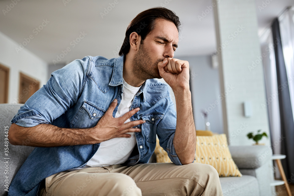 Young man feeling ill and coughing at home. Young man feeling ill and coughing at home.