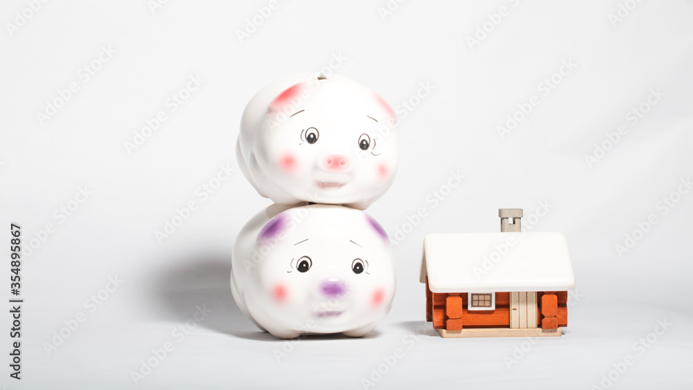 Money saving concept, modern hose model with two piggy bank stacked on white background. Money saving concept, modern hose model with two piggy bank stacked on white background.
