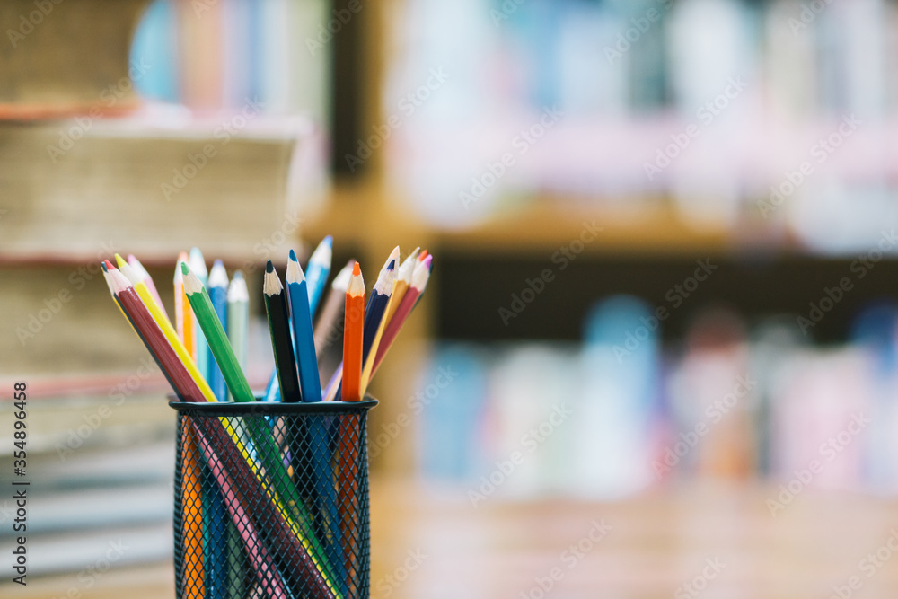 Back to school background with book and wooden color pencils in the basket. In classroom or library Back to school background with book and wooden color pencils in the basket. In classroom or library