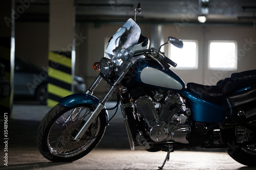 A chopper motorcycle silhouette. Motorbike standing in dark underground garage, back light