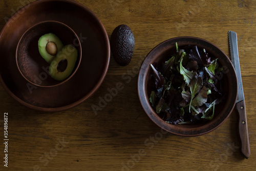 Fresh green tasty avocado lies in clay natural dishes on a wooden oak table