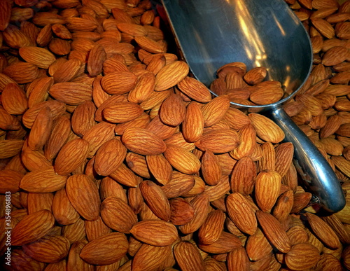 Almonds or badam in market background. Raw fresh almond nuts & metal scoop in supermarket. Organic almond badam nuts heap pattern background. Nuts badam (badaam) pile texture flat lay, snack top view photo