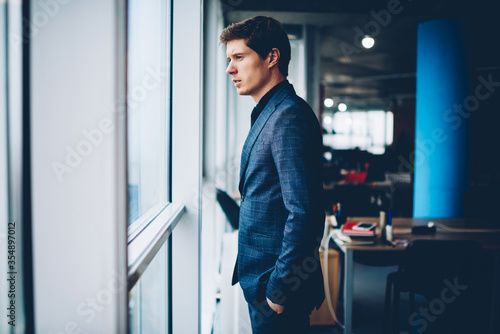 Caucasian male colleague in formal suit standing in office interior