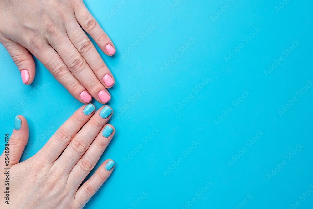 Women's hands with bright summer manicure on a blue background. Trendy colors of nail polishes for young women. Copy space Women's hands with bright summer manicure on a blue background. Trendy colors of nail polishes for young women. Copy space