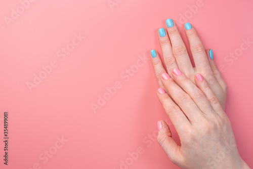 Women s hands with a bright summer manicure on a pink background. Trendy glamorous nails in fun colors. Copy space