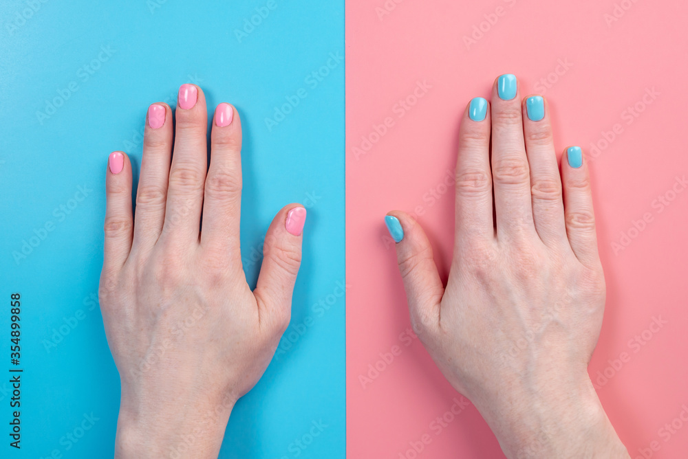 Women's hands with bright summer manicure on a blue and pink background. Trendy glamorous nails in fun colors Women's hands with bright summer manicure on a blue and pink background. Trendy glamorous nails in fun colors