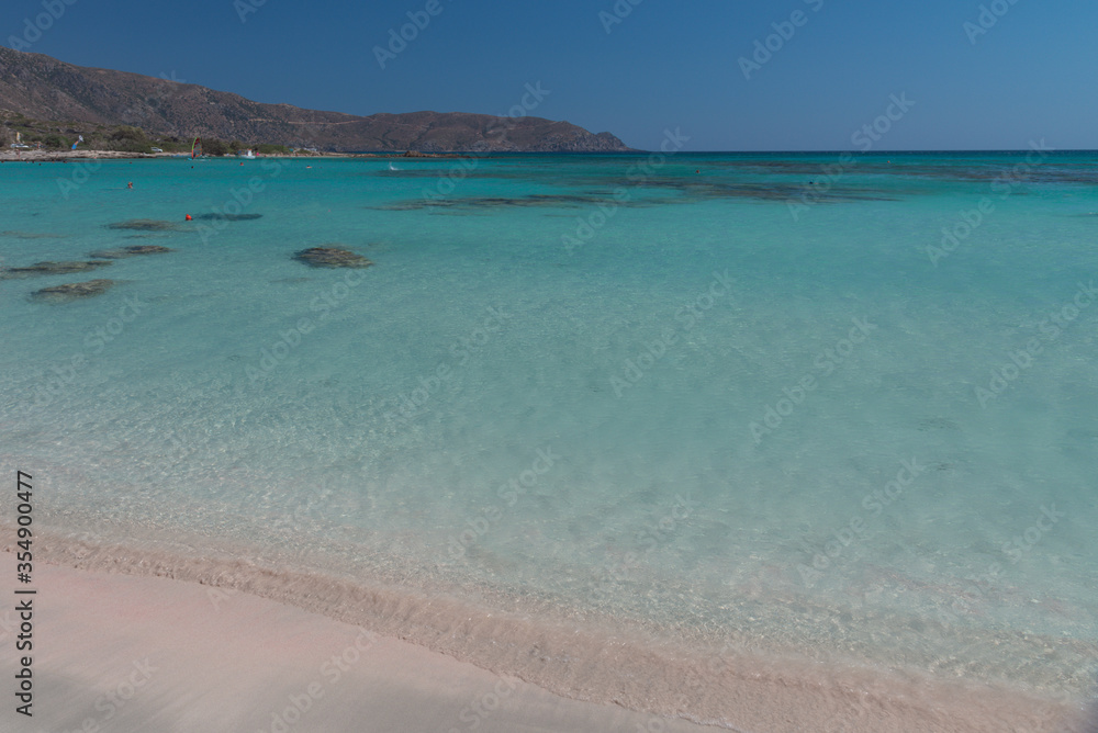 Tourists relax and bath in crystal clear water. Pink sand beach. Holiday concept