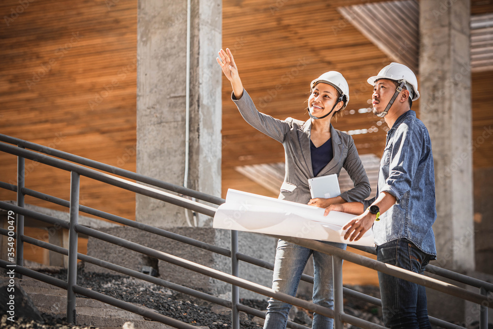 Engineer and business woman in hardhat posing on building site. civil engineer or architect with hardhat on construction site checking schedule on plan.