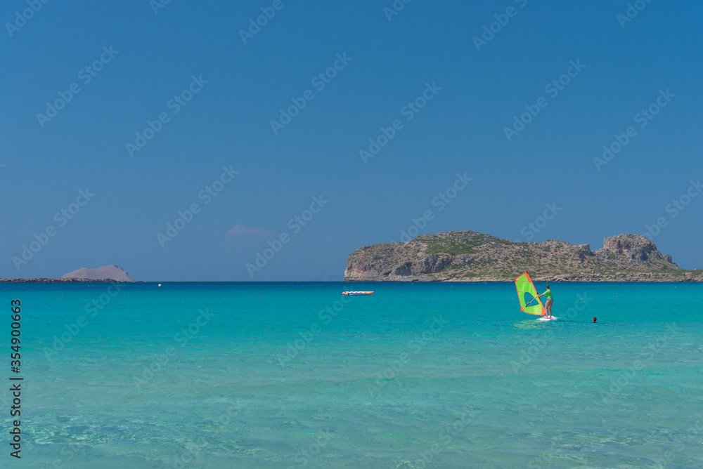 Woman windsurfing in the lagoon on the sea with mountains on the background. Active sport concept