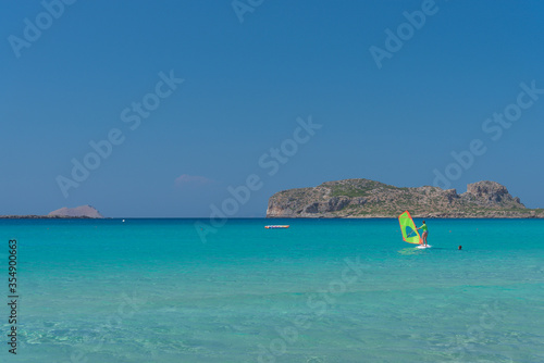 Woman windsurfing in the lagoon on the sea with mountains on the background. Active sport concept
