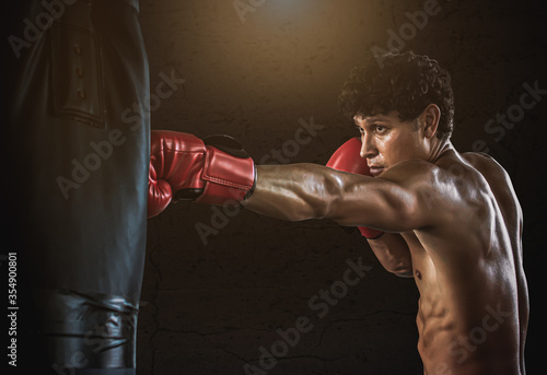 Muscular man doing exercise by boxing in gym