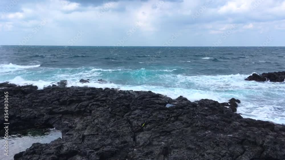 Waves hitting sea coast at Jeju Island, South Korea, waves smashing volcanic rocks in the winter Waves hitting sea coast at Jeju Island, South Korea, waves smashing volcanic rocks in the winter