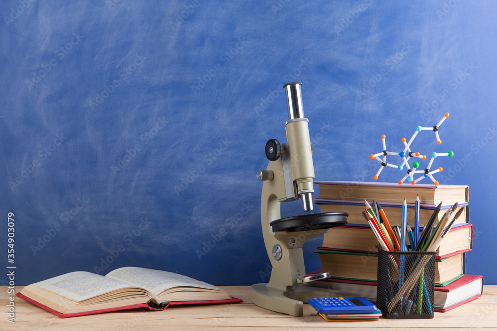 Education and sciences concept - books, molecule model and microscope ...