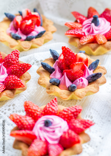 beautiful tasty cupcakes close up with strawberries, honeysuckle and pink cream