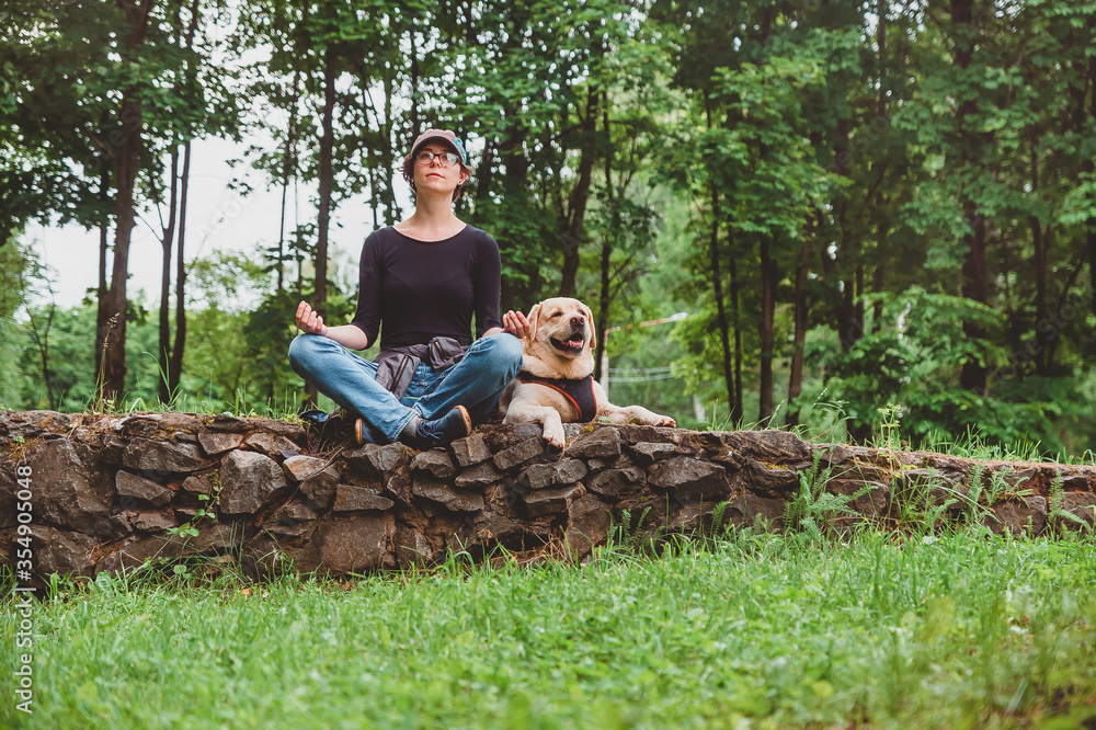 A girl with a dog meditating in the Park for a walk. Vacation with a Labrador in nature A girl with a dog meditating in the Park for a walk. Vacation with a Labrador in nature