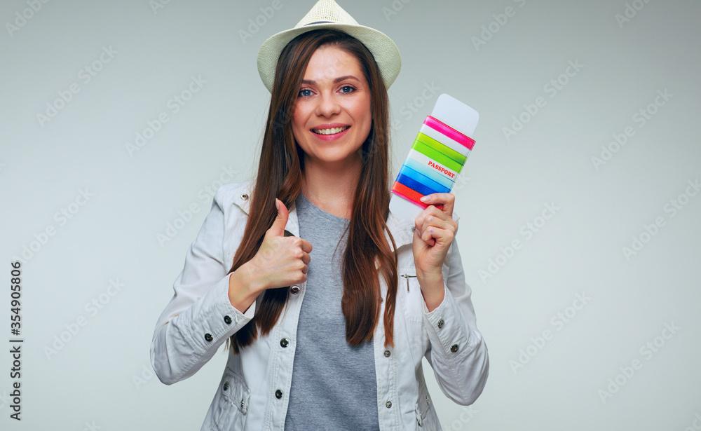 Smiling woman traveler wearing hat holding passport with ticket and showing thumb up Smiling woman traveler wearing hat holding passport with ticket and showing thumb up
