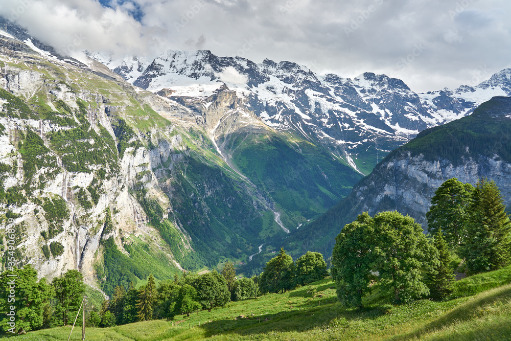 Landscape panorama of green nature of Swiss Alps. Taken between mountain villages Mürren and Gimmelwald, above Lauterbrunnen valley, Bernese Highlands, canton of Bern, Switzerland